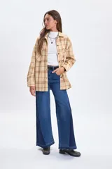Sobrecamisa de corte holgado con diseño de cuadros en tonos beige y rosado, cuello camisero, cierre frontal con botones y bolsillos delanteros en el pecho.