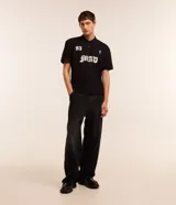 Pantalon de jean negro de corte super baggy, con tiro alto, frisos decorativos y efecto desgastado. Posee cintura con trabillas, cierre frontal tradicional y bolsillos laterales.