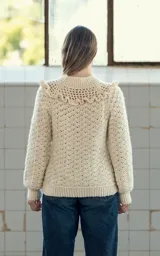 Sweater color crema tejido a crochet con lana merino, cuello alto con volados y mangas largas.