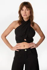 Top halter cruzado en el frente, color negro, confeccionado en lino, con diseño sin mangas y espalda descubierta.