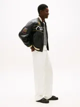 Pantalón jean blanco de corte amplio y pierna recta, con cintura ajustable en la parte trasera. Presenta cierre de cremallera con botón, dos bolsillos delanteros de parche y dos bolsillos traseros ribeteados. Detalles distintivos de la colección APXGP.