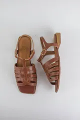 Sandalias de cuero color negro, de suela plana, con tiras entrelazadas en la capellada y tira ajustable en el talón con hebilla metálica.