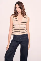 Chaleco de punto color beige con rayas horizontales negras, escote en V y cierre frontal con botones.