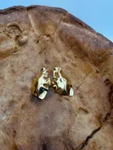 Aros dorados con diseño irregular y acabado brillante, que simulan la forma de una duna.