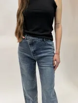 Jean de denim azul con diseño cruzado en la cintura, cierre de botón metálico y aplicaciones de strass en toda la prenda.
