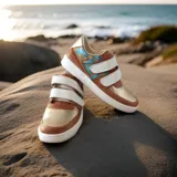 Sneakers urbanos de cuero vacuno en combinación de colores marrón terracota, blanco y dorado, con tiras de velcro y detalles pintados a mano en tono turquesa.