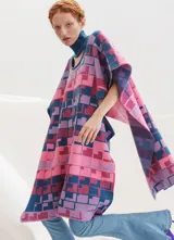 Poncho tejido con cuello alto y aberturas laterales, con diseño geométrico multicolor en tonos rosa, azul y violeta.