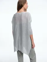 Sweater tipo túnica de tejido liviano con sutil transparencia y acabado brillante. Presenta escote en V, mangas largas relajadas y un corte amplio con largo asimétrico.