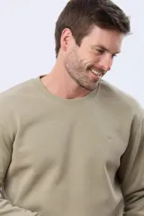 Buzo deportivo color caqui con cuello redondo, mangas largas y puños y dobladillo acanalados. Cuenta con interior en micropolar y un pequeño logo bordado al tono en el pecho.