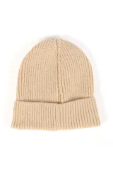 Gorro beanie tejido de punto grueso en color beige, con vuelta y pequeña etiqueta decorativa negra con la inscripción 'FEEL GOOD'.