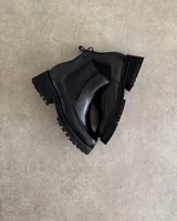 Botines Chelsea de cuero negro con elástico lateral y suela track.