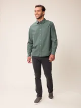 Camisa de manga larga en color azul, confeccionada en algodón con técnica de teñido garment dye. Presenta cuello abotonado, cierre frontal con botones y un bolsillo en el pecho con detalle bordado.