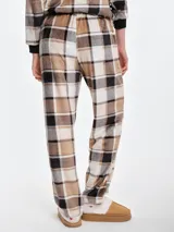 Pantalón de dormir de tela fleece con textura mullida, estampado a cuadros en tonos beige y blanco. Presenta un corte holgado con puños elastizados en los tobillos y cintura elástica.