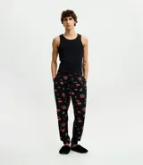 Pantalón de pijama de plush color negro con estampado de autos rojos, corte holgado, cintura elástica con cordón de ajuste y puños en los tobillos.