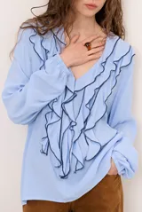 Blusa rosada de manga larga con escote en V, volados frontales con ribete negro contrastante y puños elásticos.