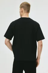 Remera negra de algodón de peso medio, corte holgado con hombros caídos y cuello redondo. Presenta un estampado frontal en blanco con el logo de la banda Oasis dentro de un recuadro y la palabra "Supersonic" debajo.