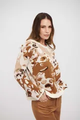 Buzo de tejido de punto con diseño abstracto en tonos tierra, cuello redondo y mangas largas. Presenta terminaciones acanaladas en puños y ruedo.