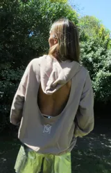 Buzo negro oversize de felpa con capucha y espalda descubierta, mangas largas, calce relajado y detalle de logo bordado en la parte inferior.