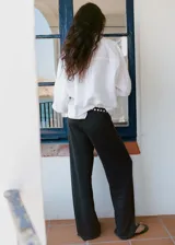 Pantalón largo gris oscuro de tiro medio, con cintura elástica y detalles de tachas metálicas redondas en el borde de la cintura, corte recto y silueta amplia.