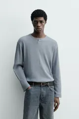 Camiseta relaxed fit de manga larga confeccionada en tejido waffle con mezcla de algodón y cáñamo. Presenta cuello redondo con cierre frontal parcial de botones.