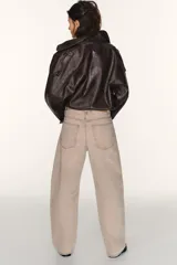 Jeans de tiro medio, color beige rosado con efecto lavado, corte amplio (baggy balloon) y detalle de costuras torcidas en el frente de las piernas.