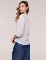 Blusa de gasa liviana blanca con estampado floral en tonos azules y rosados, escote en V, mangas 3/4 abullonadas con puños elásticos y corte fluido.