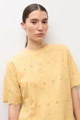 Remera blanca de manga corta con tejido de broderie, cuello redondo y diseño holgado.