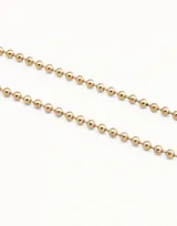 Collar de cadena formado por esferas continuas, con cierre de mosquetón y cadena de extensión. Está fabricado en una aleación de metales con baño de oro de 18k.
