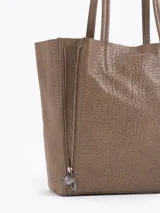 Cartera tipo shopper de cuero vacuno flor graneado, con formato amplio y estructura flexible. Presenta dos cierres verticales decorativos en el frente con tiracierres personalizados y doble manija de hombro.