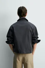 Cazadora relaxed fit de algodón color gris oscuro, con cuello solapa, manga larga con puños abotonados, bolsillos de plastrón en el pecho y cierre frontal con botonadura.