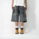 Bermuda de jean con corte baggy y lavado ácido en color negro. Presenta bolsillos laterales tipo cargo, costuras reforzadas y un bordado decorativo en color rojo en uno de los bolsillos traseros.