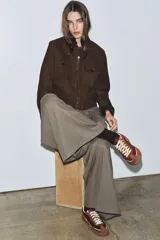 Zapatillas deportivas de caña baja con combinación de colores y materiales. El cuerpo principal es de color bordó, con refuerzos en gamuza marrón y detalles en color crema. La suela es de goma marrón. El cierre es mediante cordones gruesos color crema.