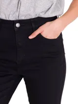 Pantalón de jean negro de corte ajustado, con diseño clásico de cinco bolsillos, cierre frontal con cremallera y botón metálico.