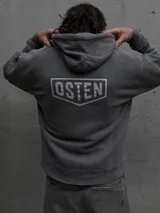 Canguro con capucha y cordones ajustables, de color gris oscuro con efecto lavado. Presenta un bolsillo frontal tipo canguro y estampado gráfico pequeño en el pecho con el logo de la marca.