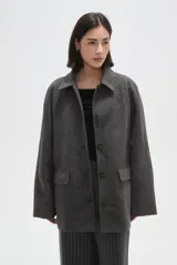 Tapado de paño color gris, con cuello camisero, cierre frontal de botones y bolsillos laterales con solapa.