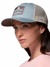 Gorra tipo trucker Columbia de color celeste con malla trasera en tono beige. Cuenta con un parche frontal bordado con diseño de montañas y el logo de la marca.