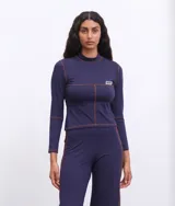 Remera de manga larga color azul marino, con cuello alto y costuras a la vista en color contraste. Presenta una pequeña etiqueta con logo en el pecho.