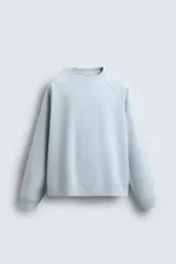 Sudadera de corte regular fit confeccionada en tejido de mezcla de algodón con estructura de piqué y efecto lavado. Presenta cuello redondo, manga larga y acabados en rib en puños y ruedo.