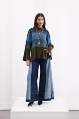 Pantalón wide leg de tiro alto confeccionado en denim de diseño bicolor, combinando tonos azul oscuro y celeste con costuras en contraste. Presenta bolsillos tipo parche en la parte inferior de las piernas y aberturas en los puños.