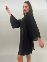 Vestido corto de gasa con estampado abstracto en tonos grises y negros. Tiene escote cuadrado, mangas 3/4 plisadas, bolsillos laterales ocultos y espalda levemente escotada con elástico a la altura de la cintura.