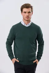 Buzo tejido de algodón color gris melange, de diseño clásico con escote en V, mangas largas y puños y ruedo acanalados. Cuenta con un pequeño bordado en el pecho.