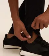 Pantalón deportivo de corte ajustado, color negro, con cintura elástica, cordón de ajuste, bolsillos laterales con cremallera, bandas laterales en contraste y cremalleras en los tobillos.