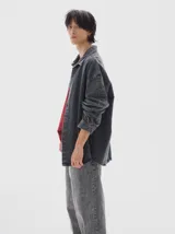 Camisa de denim de manga larga con cuello clásico, cierre frontal de botones y diseño oversize con lavado tipo washed.