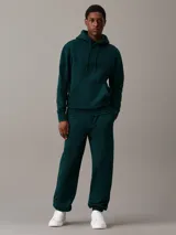 Pantalón de chándal verde oscuro de felpa gruesa con cintura y puños elásticos, bolsillos laterales y traseros, corte recto y holgado. Con bordado de Calvin Klein en la cadera.