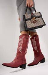 Botas texanas de cuero negro con bordados decorativos en el lateral de la caña, punta fina y taco bajo.