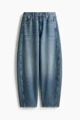Jean de tiro alto y corte baggy, confeccionado en denim de algodón rígido en tono azul medio con efecto deslavado. Presenta diseño de cinco bolsillos, trabillas para cinto y cierre frontal con botón y cremallera.