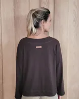 Remera de manga larga color marrón chocolate, con cuello redondo y dos bolsillos frontales tipo parche.