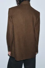 Blazer marrón de la colección Zara Woman, confeccionada en hilatura con 38% lana. Presenta cuello subido, manga larga con abertura y botones, bolsillos con solapa en el delantero y forro interior. Cierre frontal con un botón.