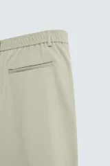 Bermuda de hombre color verde claro, de corte regular y tiro medio, con pinzas frontales, bolsillos laterales y bolsillos traseros de vivo. Cierre frontal con botón y cremallera.