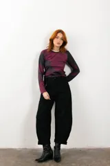 Pantalón negro de corte ancho con bolsillos laterales y cadena metálica decorativa.